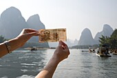 Li-Fluss, Yangshuo, China; Person hält chinesische Währung hoch