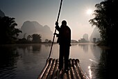 Mann auf Floß in Berggebiet; Yulong-Fluss, Yangshuo, China