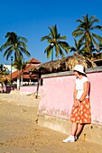 Santa Cruz Beach, Huatulco, Bundesstaat Oaxaca, Mexiko; Frau lehnt sich an eine Wand am Strand