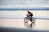 Puerto Vallarta, Mexiko; Frau beim Radfahren am Strand