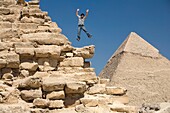 Mann springt auf einem Teil einer Pyramide in der Wüste