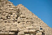 Mann sitzend auf einem Teil einer Pyramide in der Wüste