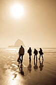 Vier Menschen gehen am Strand spazieren; Cannon Beach, Oregon, USA