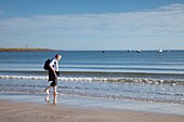 Mann geht am Strand entlang, Northumberland, England