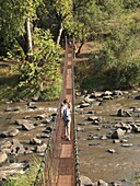 Mädchen spaziert auf Hängebrücke, Kenia, Afrika