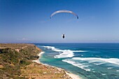 A Paraglider Soars Free Over The Cliffs Of The Bukit Peninsula In Bali; Bali,Indonesia