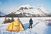 Mann neben einem Zelt im Schnee; Kananaskis, Alberta, Kanada