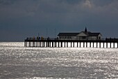 Southwold, Suffolk, England; Fishermen Standing On A Pier And A Building Along The Coast Of The North Sea