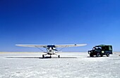 Flugzeug und Safari-Fahrzeug auf Salzpfannen