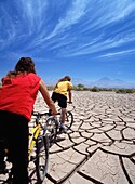Zwei Radfahrer, die über rissigen Schlamm in der Atacama-Wüste fahren