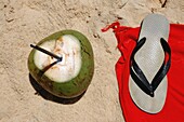 Kokosnussgetränk und Flip Flop am Strand, Nahaufnahme