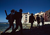 Silhouetten von Menschen, die neben einem kleinen Strand spazieren gehen; St. Tropez, Frankreich