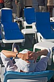 Ein Passagier sitzt und entspannt sich auf dem Sonnendeck eines Kreuzfahrtschiffes