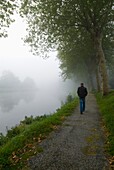 Mann geht an einem nebligen Morgen am Nantes-Brest-Kanal entlang