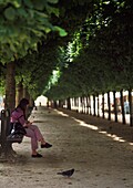 Eine Frau liest ein Buch in den Gärten des Palais Royale.