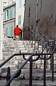 Frau geht eine Treppe im Viertel Le Panier hinauf