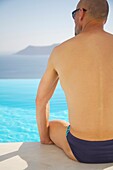 Man Sitting By Swimming Pool By Sea