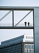 Zwei Männer auf der Brücke zwischen Regierungsgebäuden auf beiden Seiten der Spree