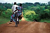 Family Cycling Home On A Dirt Road