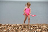 Kind im rosa Badeanzug beim Spielen am Strand