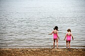 Sisters In Matching Pink Bathing Suits Playing On Beach