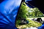 View Through Tent Of Campsite And Woman Reading