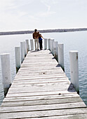 Couple Hugging At The End Of A Pier