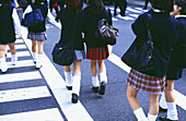 Schulmädchen in Uniformen gehen über den Cross Walk
