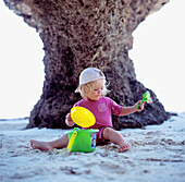 Kind spielt mit Plastikspielzeug am Strand