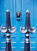 Blaue Tür mit Löwentürklopfer, gesehen durch einen Eisenzaun, London