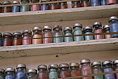 Gefäße mit bunten Farbstoffen in Flaschen auf Regalen