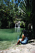 Frau sitzt am Rande eines natürlichen Pools, Isalo National Park
