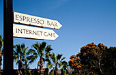 Schild für Expresso-Bar und Internet-Café mit Palmen im Hintergrund