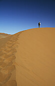 Person klettert auf Sanddünen in der Namib-Wüste