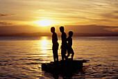 Silhouette eines Jungen auf einem Boot bei Sonnenuntergang