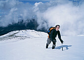 Frau klettert einen verschneiten Hang in der Sierra Nevada hinauf