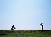 Tourist mit Sonnenschirm und Mann auf Fahrrad