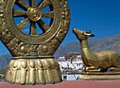 Hirschstatuen und Dharma-Rad auf dem Gipfel des Jokhang-Tempels mit dem Potala-Palast im Hintergrund