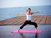 Westliche Frau macht Yoga auf einem Kreuzfahrtschiff