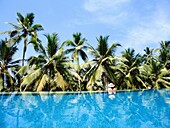 Woman In Infinity Pool And Palm Trees