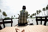 Tourist Riding On A House Boat While Local Steers