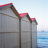 Strandhütten in Mondello, die zum Meer führen, mit einer Yacht in der Ferne