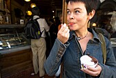 Frau isst Eiscreme außerhalb einer Gelaterie