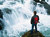 Wanderer schaut über einen kleinen Wasserfall.