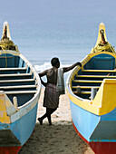 Man Leaning On Fishing Boats On Beach