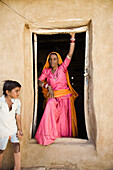 Frau in buntem Sari steht in der Tür eines Hauses