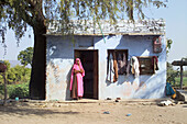 Woman In Pink Sari Standing In Doorway Of Her Village House
