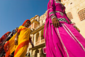 Four Women In Colorful Saris Walking Past Old Building