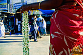 Frau verkauft Blumengirlande auf der Straße, Mittelansicht