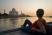 Tourist sitzt auf dem Deck eines Bootes und bewundert das Taj Mahal
